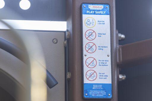 Playground safety signage at the Somerville Park tube slide entry, with height and safe-use instructions.